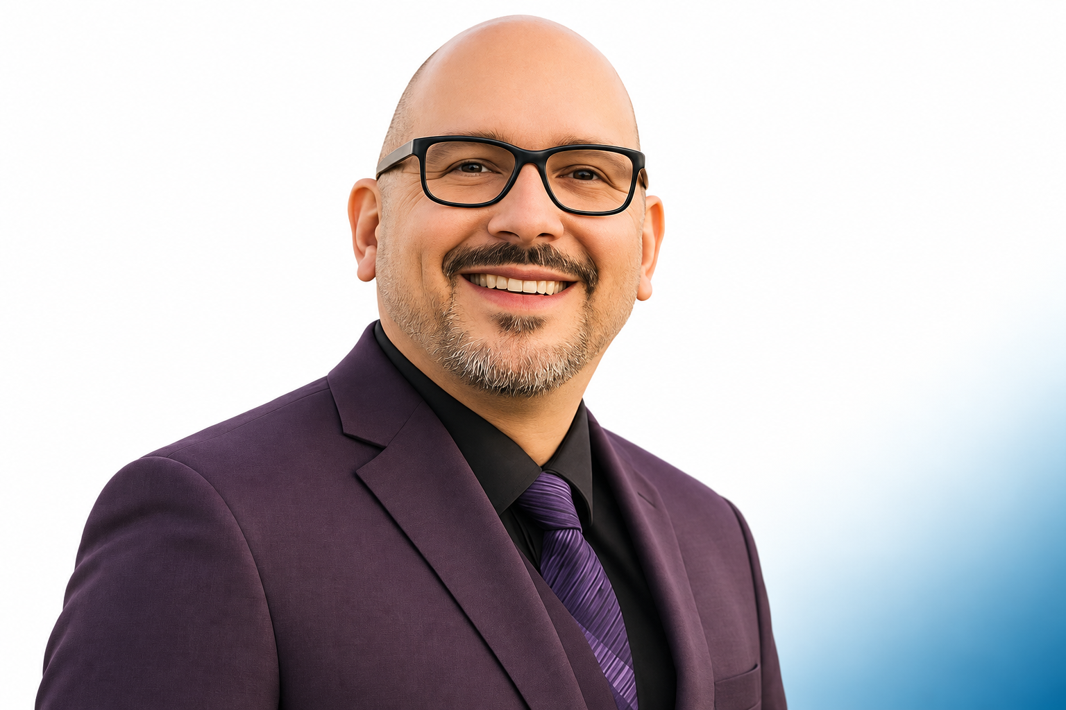 Michael Azcona smiling in a dark suit and glasses